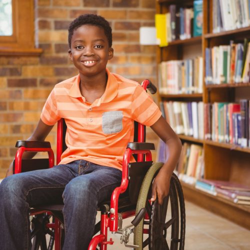 Portrait of little boy sitting in wheelchair at the library